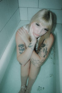 a woman sitting in a bathtub with tattoos